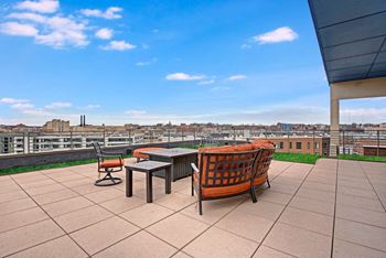 Rooftop terrace with outdoor fireplace and grill overlooking stunning skyline views